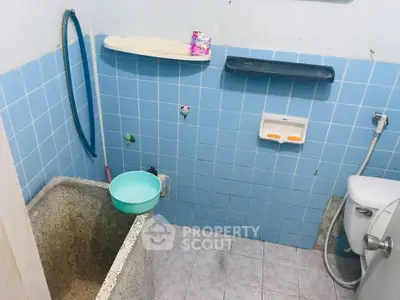 Compact bathroom with blue tiles and basic fixtures, featuring a traditional wash basin and toilet.