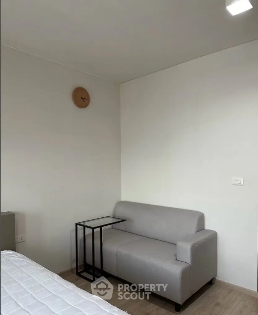 Modern minimalist living room with sleek gray sofa and stylish side table, perfect for cozy relaxation.