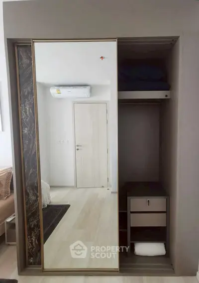 Modern bedroom with sleek mirrored wardrobe and air conditioning unit.