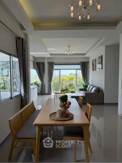 Elegant dining and living area with garden view, modern lighting, and stylish decor.