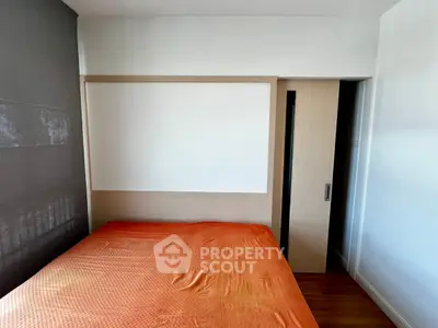 Cozy bedroom with orange bedding and sliding door in modern apartment