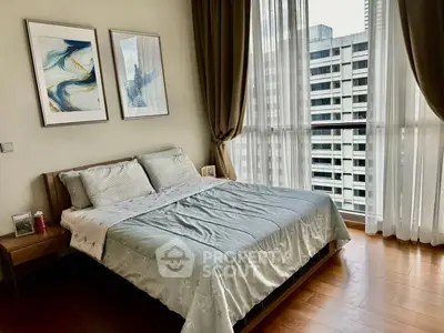 Modern bedroom with large windows and city view, featuring stylish decor and wooden flooring.