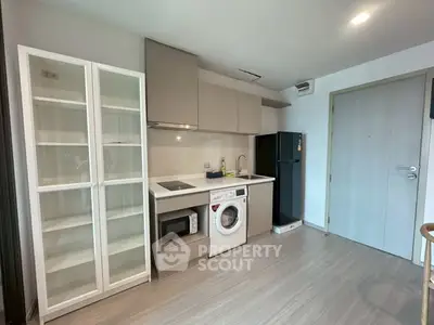 Modern kitchen with sleek cabinetry, washing machine, and refrigerator in a compact layout.