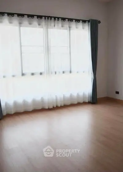 Spacious empty room with large windows and wooden flooring, perfect for customization.