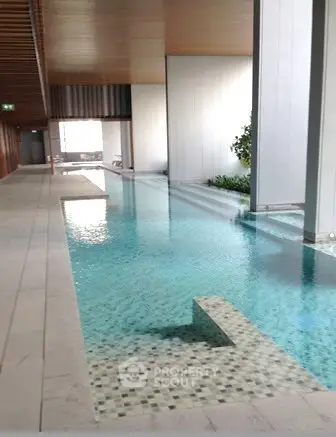 Luxurious indoor pool with modern design and serene ambiance in upscale residential building.
