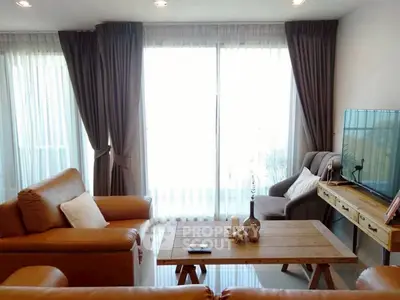 Stylish living room with leather sofas and large windows offering natural light.