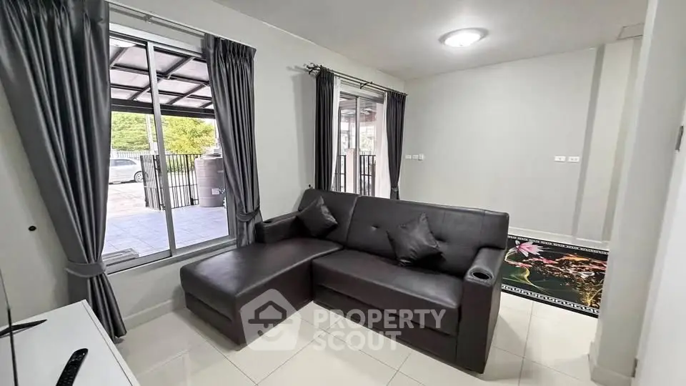 Modern living room with sleek black sofa and large window offering natural light