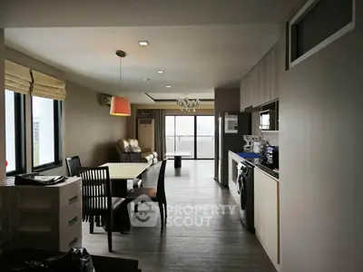 Spacious modern living room with dining area and balcony view, featuring sleek furniture and natural light.