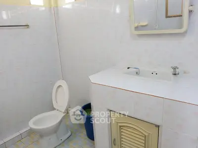 Spacious bathroom with tiled walls, sink, and toilet in a well-lit setting.