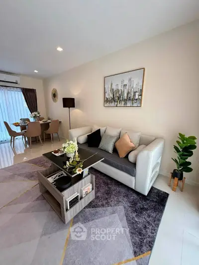 Modern living room with stylish decor and open dining area, featuring elegant furniture and contemporary artwork.