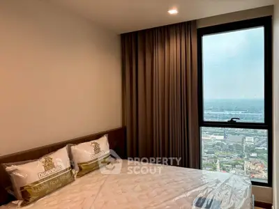 Modern bedroom with large window offering stunning city view, featuring cozy bed and elegant curtains.