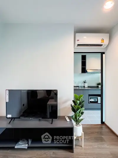 Modern living room with sleek TV setup and view into a stylish kitchen
