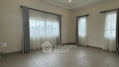 Spacious empty room with large windows and elegant curtains, perfect for customization.