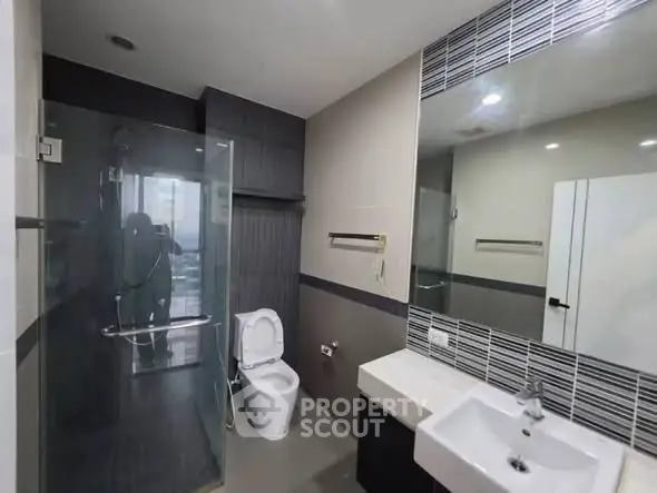 Modern bathroom with glass shower and sleek fixtures in contemporary apartment.