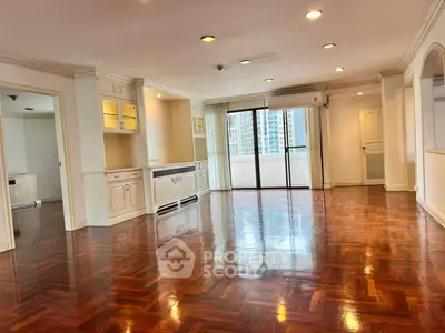Spacious living room with polished wooden floors and city view balcony.