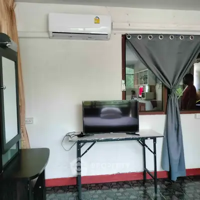 Cozy living space with air conditioning and TV, featuring a window view into the kitchen area.