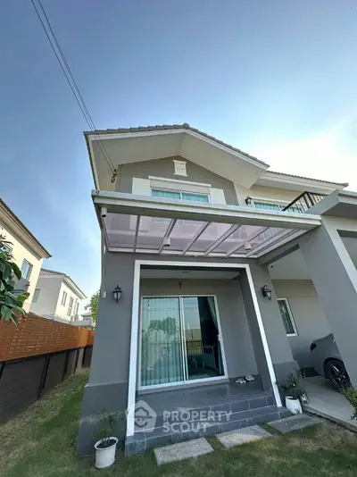 Modern two-story house exterior with balcony and garden view