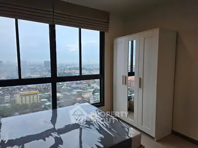 Modern bedroom with large window offering stunning city view and sleek wardrobe.
