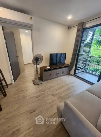 Modern living room with balcony view and sleek wooden flooring.