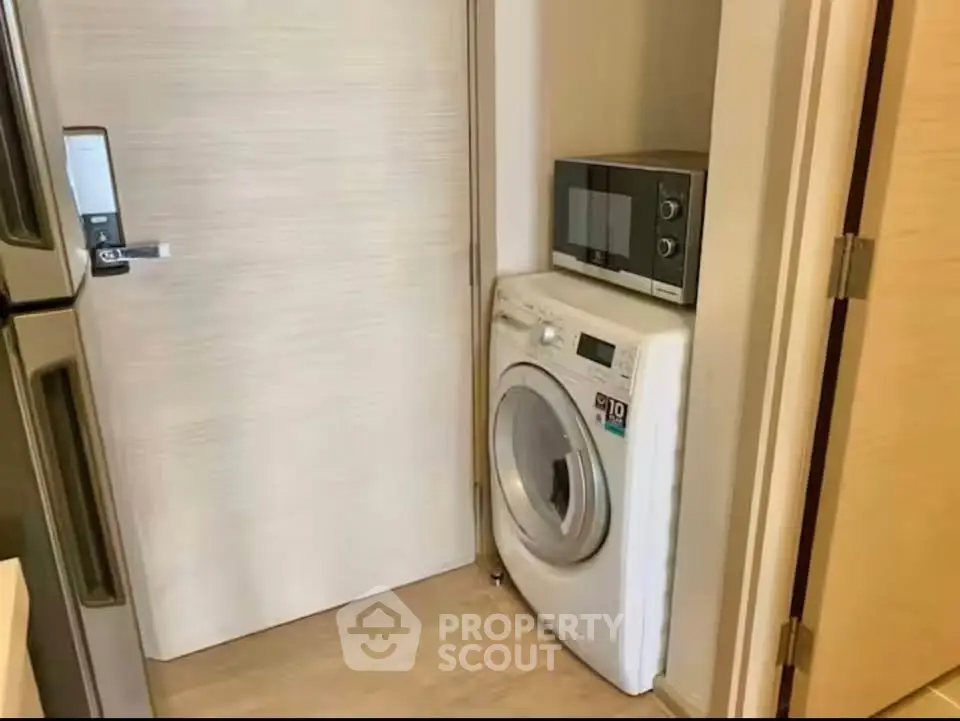 Compact laundry area with washing machine and microwave in modern apartment.