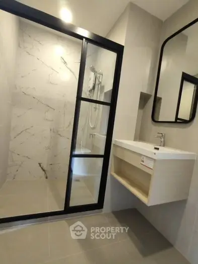 Modern bathroom with sleek shower and elegant vanity in contemporary apartment.