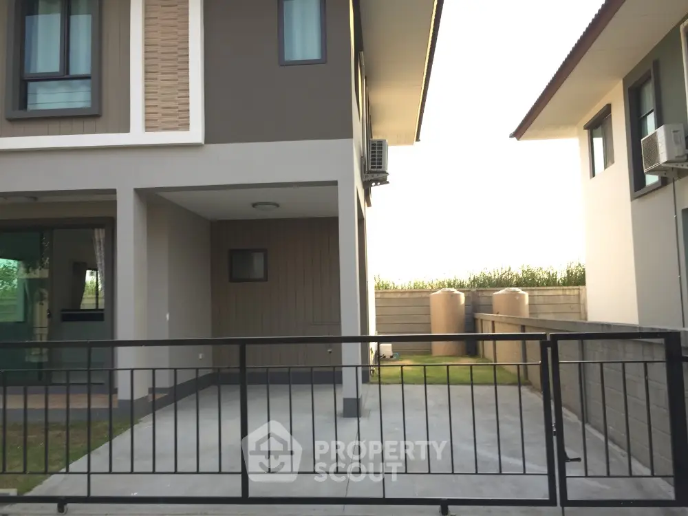 Modern townhouse exterior with gated driveway and green lawn