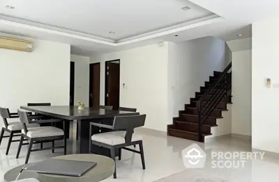 Spacious modern dining area with elegant staircase and sleek furniture