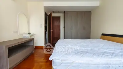 Spacious bedroom with wooden flooring and modern furniture in a cozy apartment.