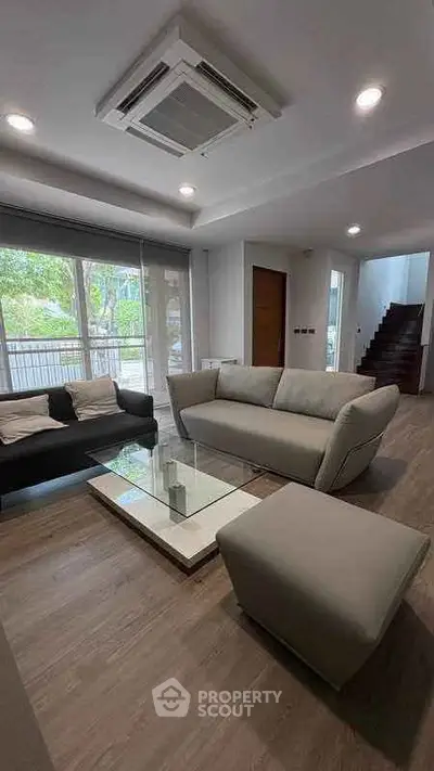 Modern living room with stylish furniture and large windows offering natural light and garden view.