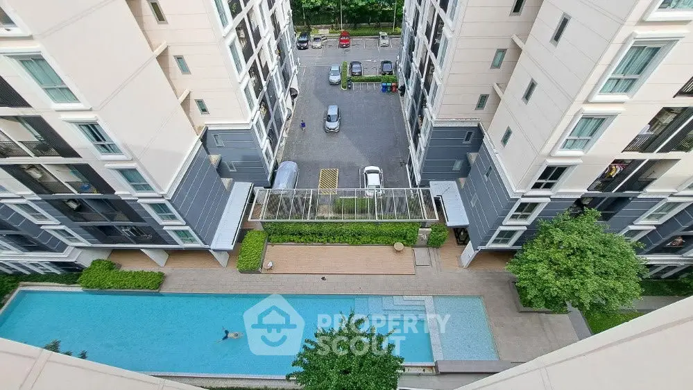Stunning aerial view of modern apartment complex with pool and parking area.