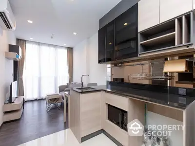 Modern kitchen with sleek black appliances flows into a cozy living area with ample natural light, perfect for urban living.