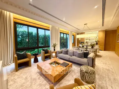 Luxurious open-plan living room with elegant decor and large windows overlooking lush greenery.