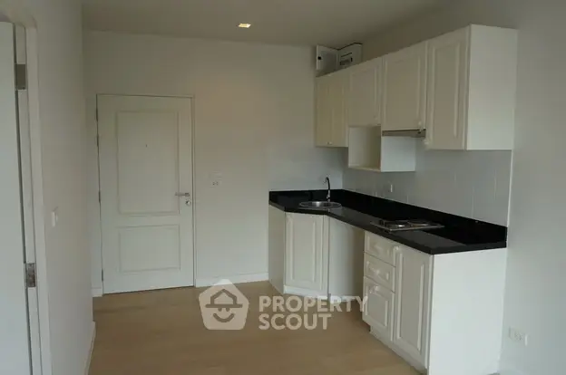 Modern compact kitchen with sleek white cabinets and black countertops