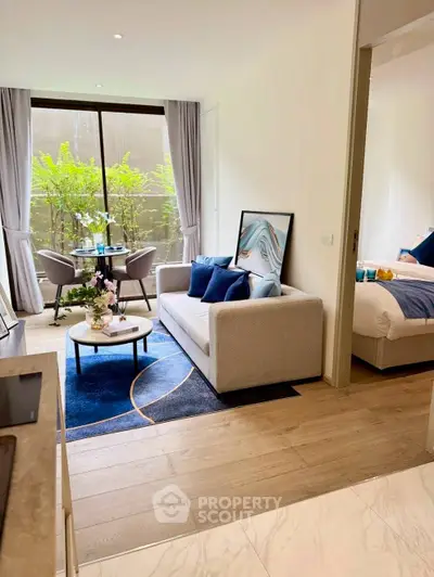 Modern open-plan living room with stylish decor and natural light, adjacent to a cozy bedroom.
