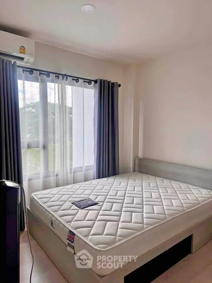 Cozy bedroom with large window and natural light, featuring a comfortable bed and modern decor.