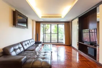 Spacious living room with leather sofa and large window opening to balcony view.
