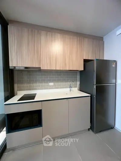 Modern kitchen with sleek cabinetry and stainless steel fridge in a compact layout.