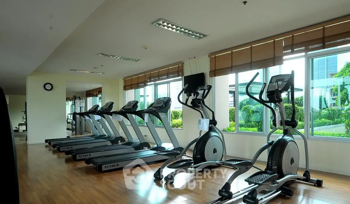 Spacious gym with modern equipment and large windows offering garden views.