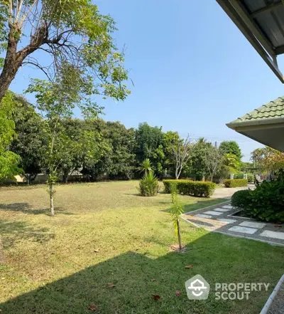 Spacious garden view with lush greenery and paved walkway in serene residential area.