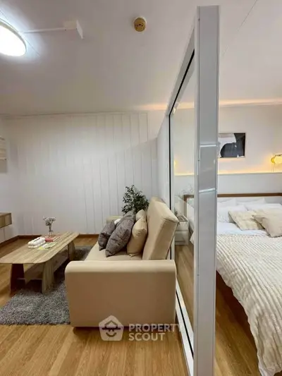 Modern studio apartment with cozy living area and stylish bedroom separated by glass partition.