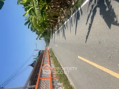 Scenic road with lush greenery and traditional architecture, perfect for serene living.