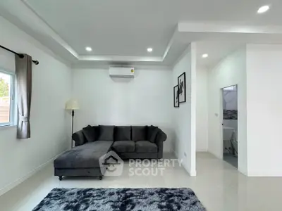 Modern living room with sleek gray sofa, plush rug, and elegant lighting in a bright, minimalist space.