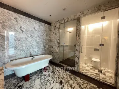 Luxurious marble bathroom with freestanding bathtub and glass-enclosed shower.