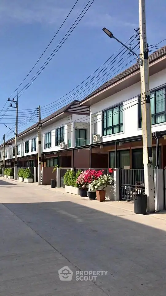 Modern townhouse exterior with clean lines and vibrant landscaping in a sunny neighborhood.