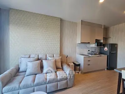 Modern living room with cozy sofa and compact kitchen in open layout apartment.