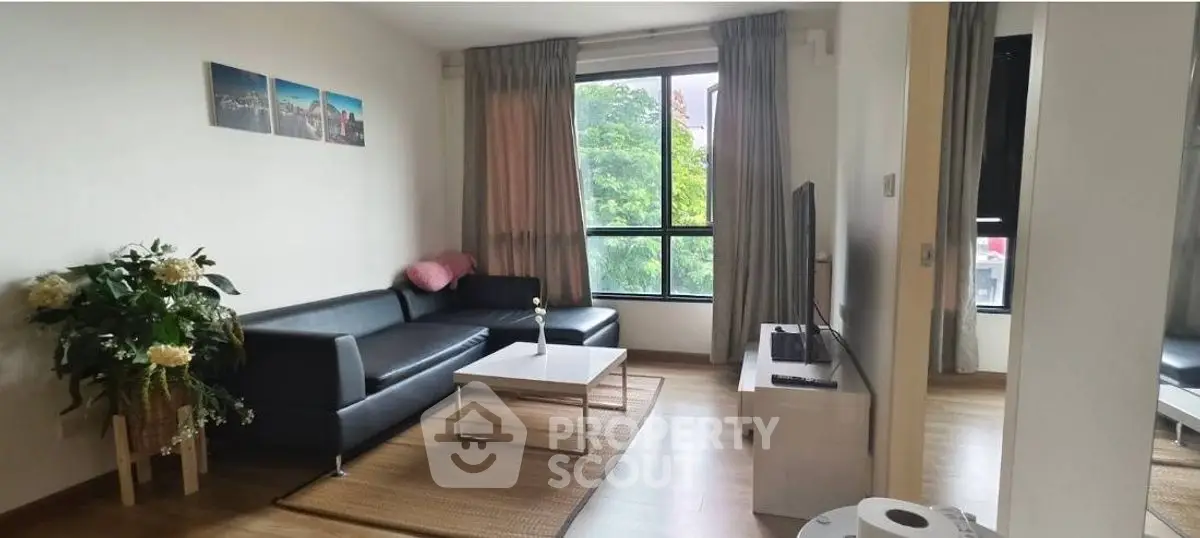 Modern living room with black leather sofa, large window, and stylish decor.