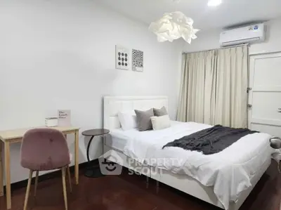 Modern bedroom with stylish decor, featuring a cozy bed, elegant lighting, and a chic workspace.