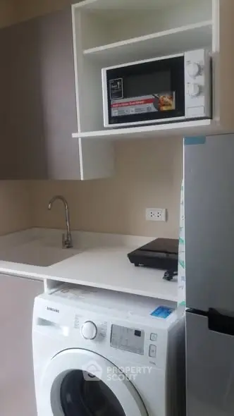 Compact kitchen with modern appliances including washing machine and microwave.