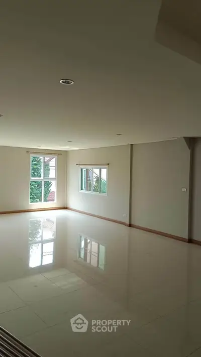 Spacious empty living room with large windows and glossy tiled floors.