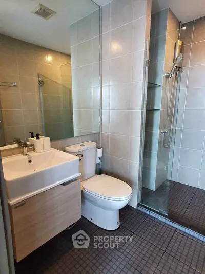 Modern bathroom with sleek fixtures and glass shower enclosure in contemporary apartment.